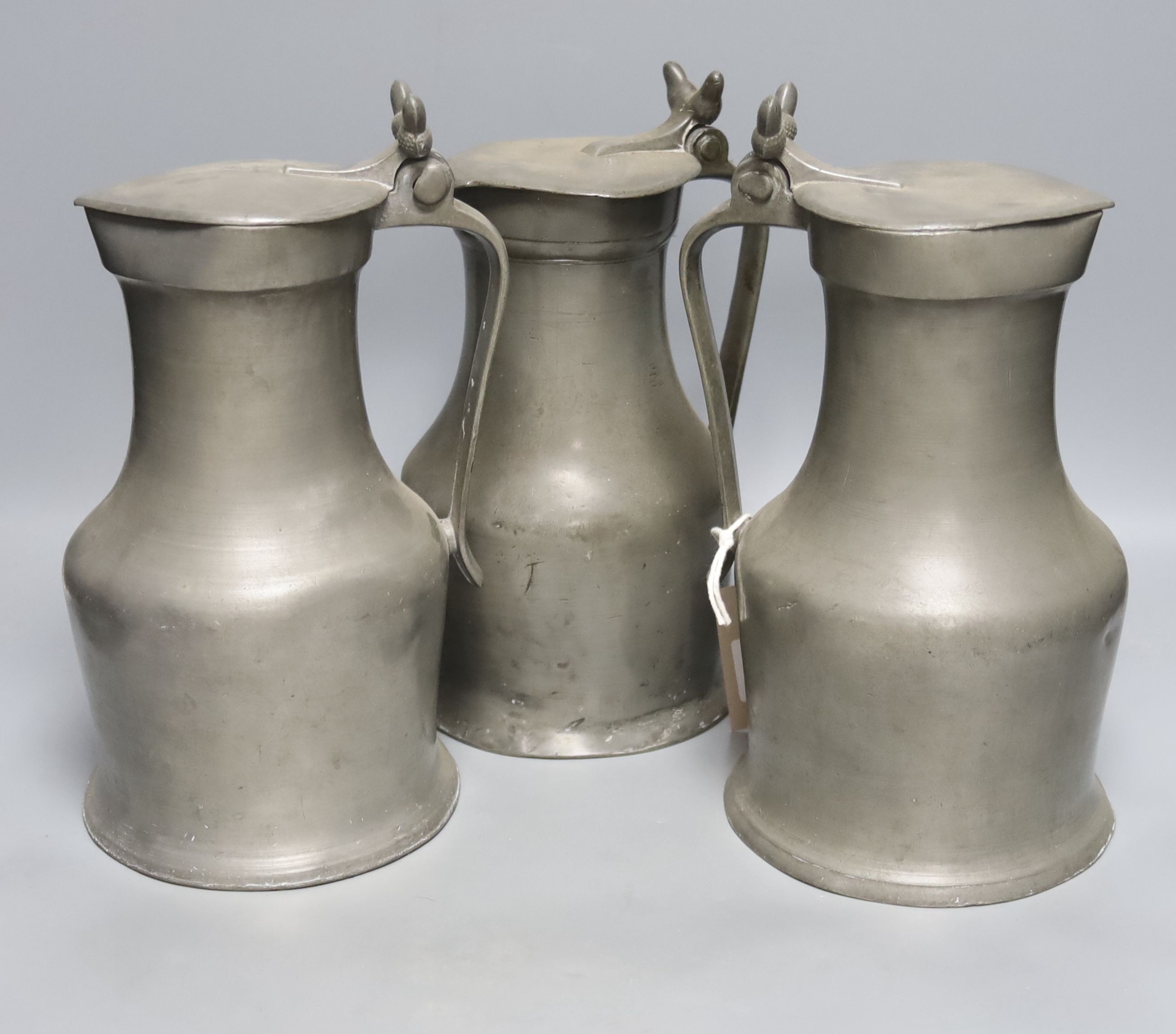 Three 18th century French pewter flagon measures, tallest 27cm, one marked